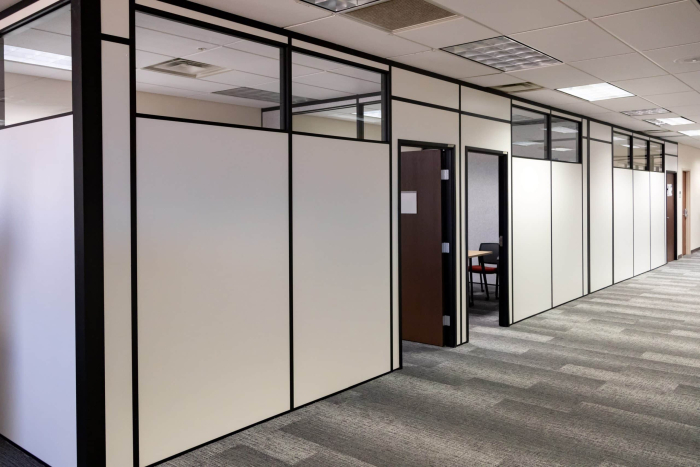 Office hallway with modular partition walls and private offices built by Allied Modular using black-framed white panels and upper glass inserts.