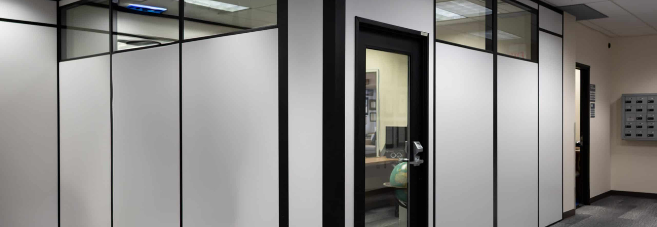 Modular office enclosure built by Allied Modular featuring black-framed panels with glass upper sections and a glass door.