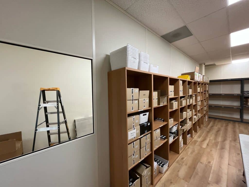 Allied Modular modular office partition walls separating a storage area with shelving units.