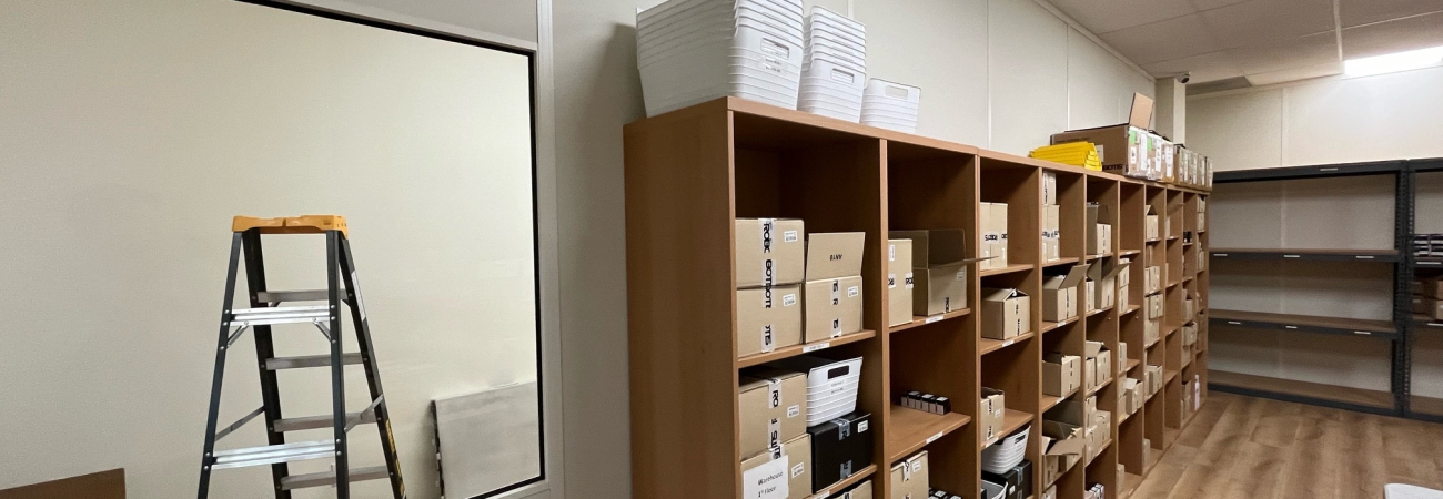 Allied Modular modular office partition walls separating a storage area with shelving units.