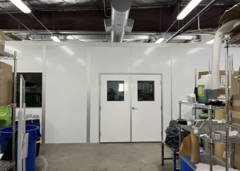 White modular laser welding enclosures by Allied Modular with double doors and overhead ventilation ducting.