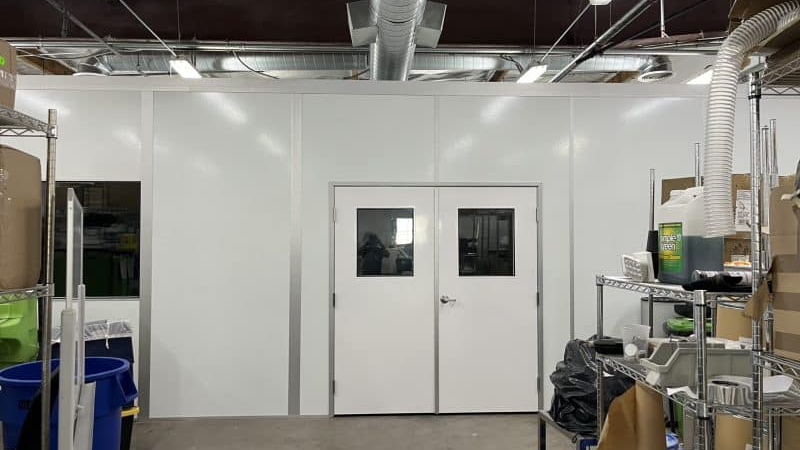 White modular laser welding enclosures by Allied Modular with double doors and overhead ventilation ducting.