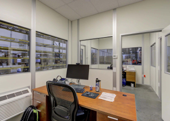 Indoor modular office by Allied Modular with desk, chair, and computer setup inside a warehouse environment.